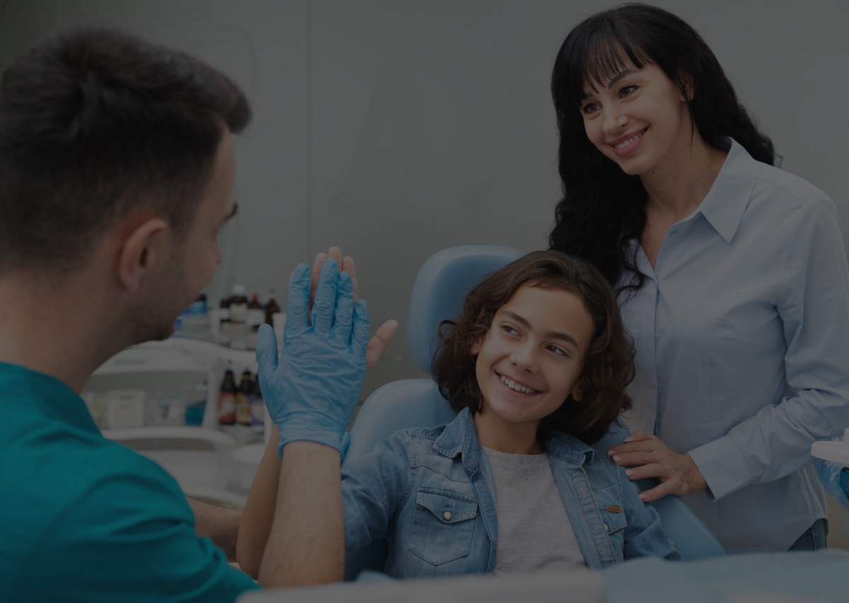 Young patient high-fiving her dentist after a dental check-up