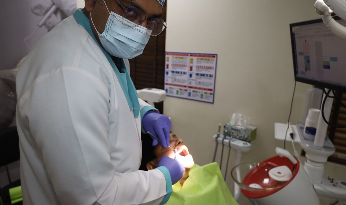 Dentist examining a patient's mouth during a chairside check-up at Dental Quest, Dwarka